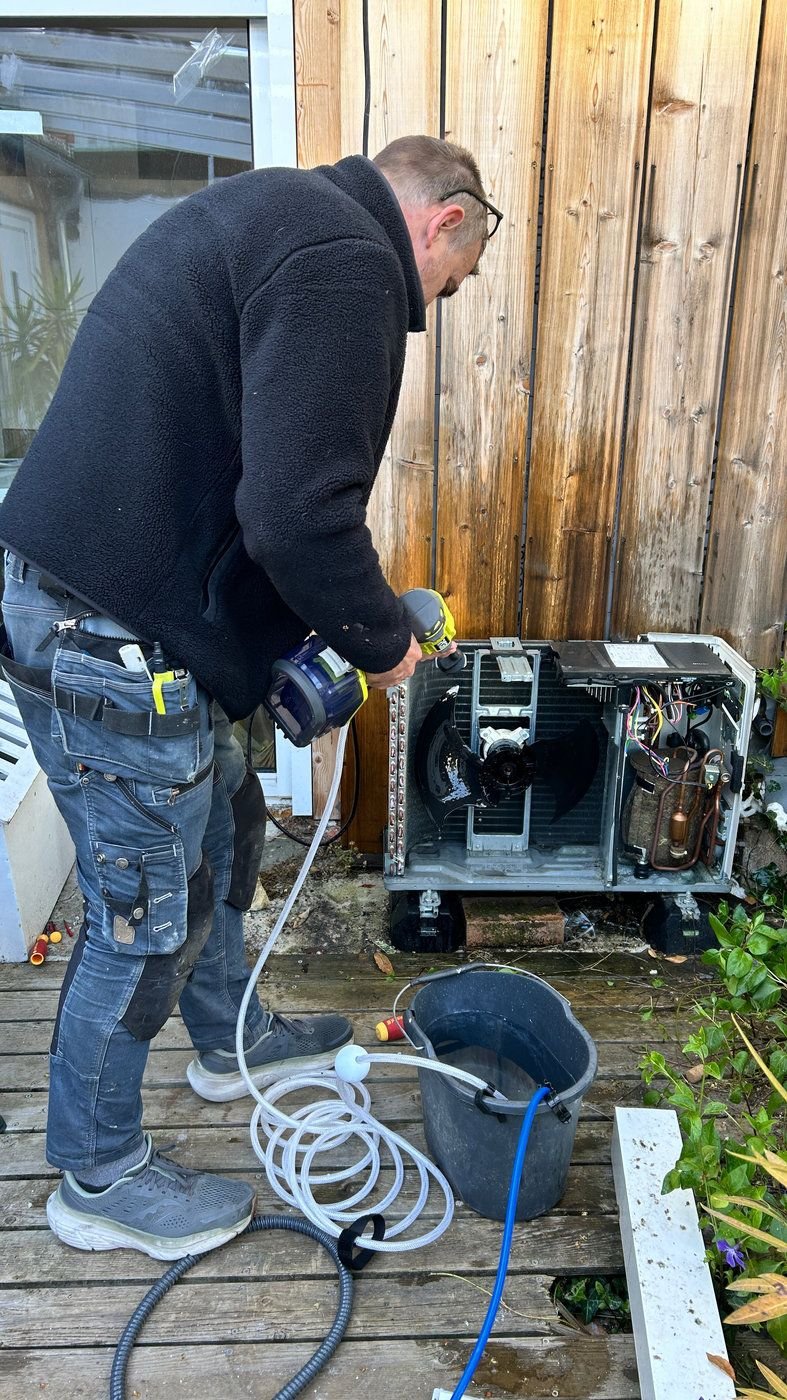 Un technicien Atouservices sur une unité de climatisation